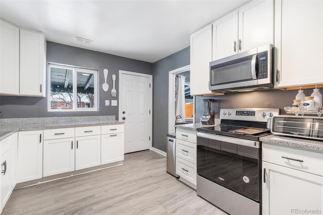 kitchen featuring white cabinetry, plenty of natural light, stainless steel appliances, and light hardwood / wood-style flooring