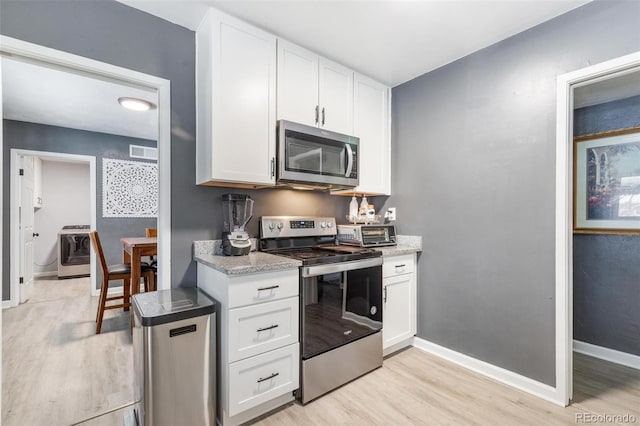 kitchen with appliances with stainless steel finishes, washer / clothes dryer, light hardwood / wood-style flooring, and white cabinets