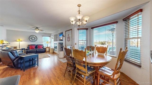 dining space featuring ceiling fan with notable chandelier, built in shelves, and hardwood / wood-style flooring