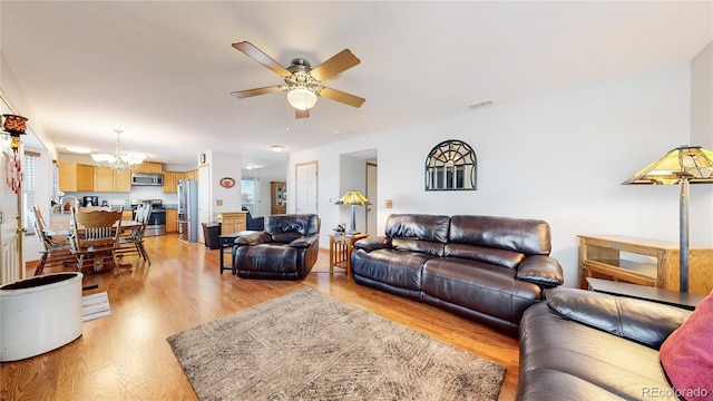 living room featuring light wood-type flooring and ceiling fan with notable chandelier