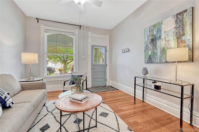 living room featuring a ceiling fan, baseboards, and wood finished floors