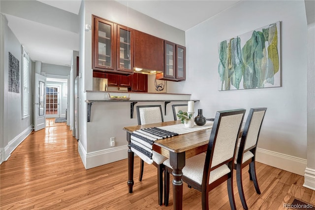 dining space featuring baseboards and light wood-type flooring