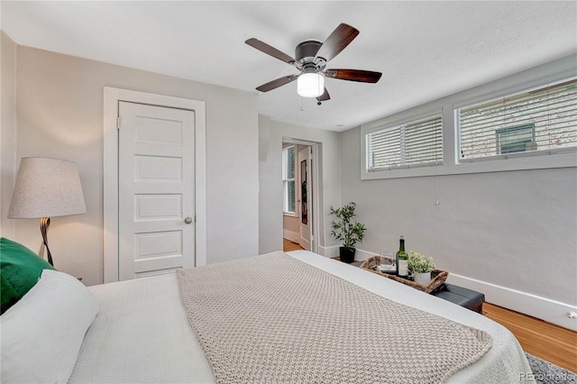 bedroom featuring a ceiling fan, baseboards, and wood finished floors