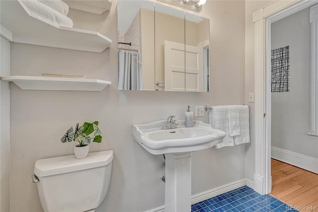 bathroom with toilet, tile patterned floors, and baseboards