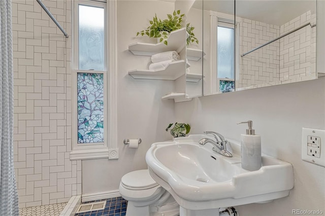 bathroom with visible vents, a tile shower, and toilet