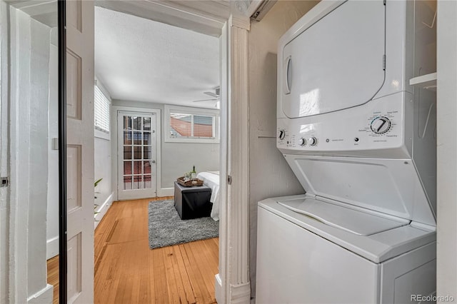 washroom with light wood-style floors, laundry area, and stacked washer / dryer
