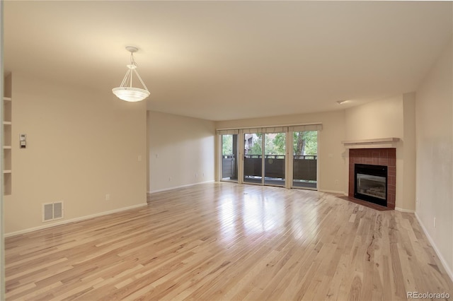 unfurnished living room featuring a tile fireplace and light wood-type flooring