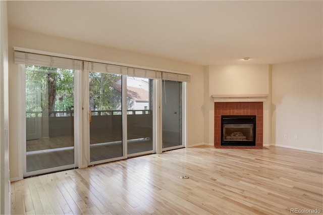 unfurnished living room featuring a tile fireplace and light hardwood / wood-style floors