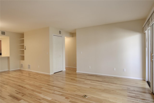 unfurnished room featuring built in features and light wood-type flooring