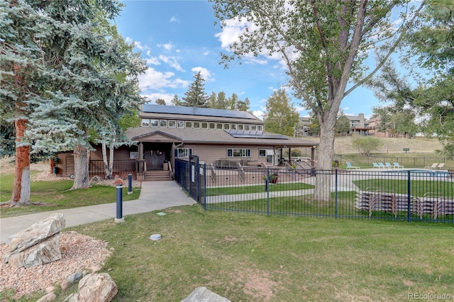 view of front of home featuring a front lawn, solar panels, and covered porch