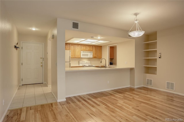 kitchen with pendant lighting, sink, white appliances, light hardwood / wood-style flooring, and kitchen peninsula