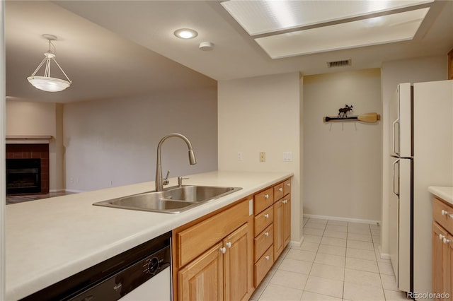 kitchen with sink, white appliances, light tile patterned floors, a tile fireplace, and hanging light fixtures