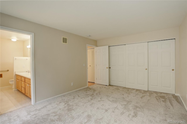 unfurnished bedroom with connected bathroom and light carpet