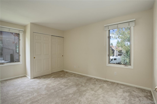 unfurnished bedroom featuring light colored carpet and a closet