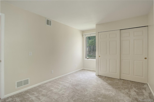 unfurnished bedroom featuring light colored carpet and a closet