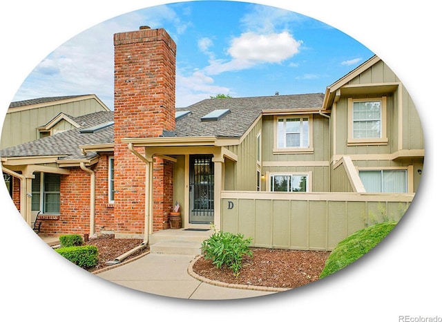 7781 S Curtice Dr Unit D, Littleton, CO 80120 - view of front facade featuring a chimney and a shingled roof