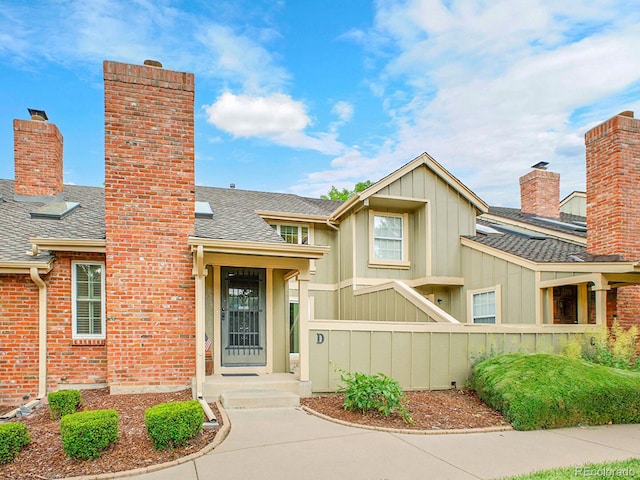 7781 S Curtice Dr Unit D, Littleton, CO 80120 - view of front of house with a chimney, roof with shingles, and board and batten siding