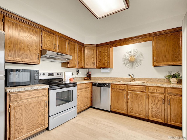 7781 S Curtice Dr Unit D, Littleton, CO 80120 - kitchen featuring appliances with stainless steel finishes, under cabinet range hood, light wood-style floors, and light countertops