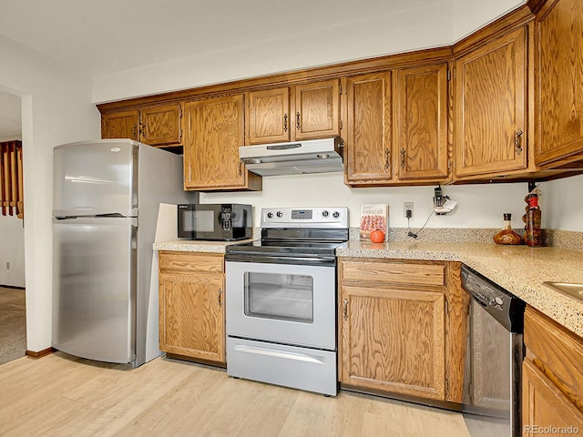 7781 S Curtice Dr Unit D, Littleton, CO 80120 - kitchen featuring under cabinet range hood, appliances with stainless steel finishes, light wood finished floors, and brown cabinetry