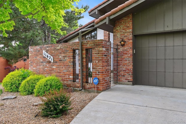 11621 Shoshone Way, Denver, CO 80234 - property entrance with brick siding, an attached garage, and driveway