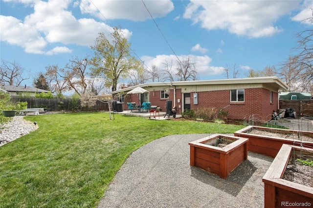 6188 S Westview St, Littleton, CO 80120 - back of house featuring a fenced backyard, a patio, a garden, and brick siding