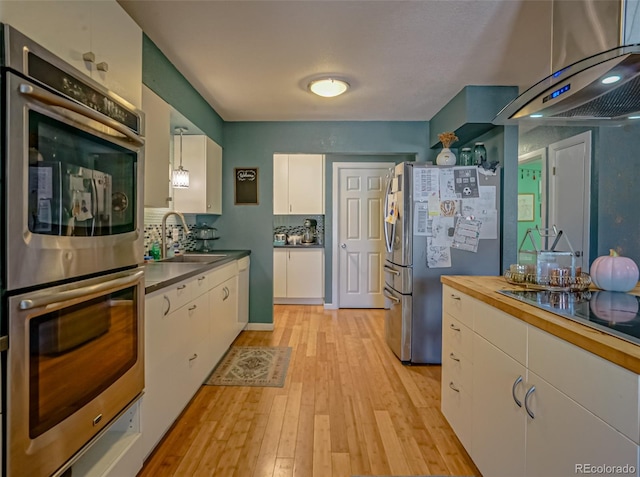 kitchen featuring stainless steel appliances, light hardwood / wood-style floors, white cabinetry, sink, and pendant lighting