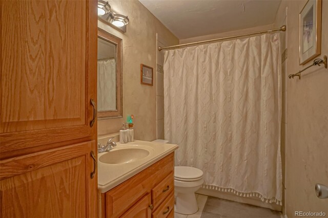 bathroom featuring vanity, toilet, tile patterned floors, and walk in shower