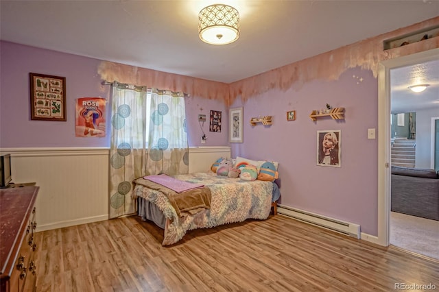 bedroom with baseboard heating and light hardwood / wood-style flooring