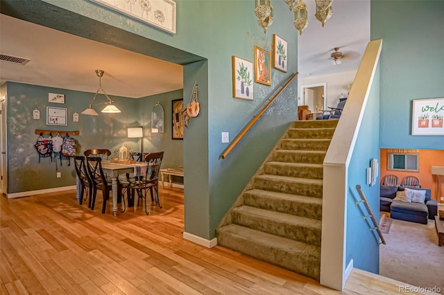 stairs featuring ceiling fan and hardwood / wood-style flooring