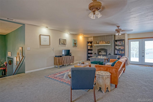 living room featuring carpet flooring, ceiling fan, a tiled fireplace, and french doors