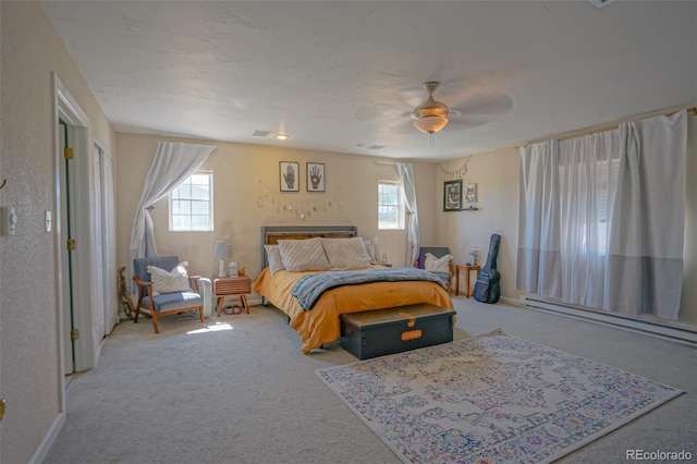 carpeted bedroom featuring a baseboard heating unit and ceiling fan