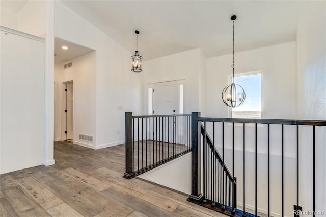 16990 Early Light Dr, Colorado Springs, CO 80908 - hall featuring visible vents, a notable chandelier, wood finished floors, and an upstairs landing
