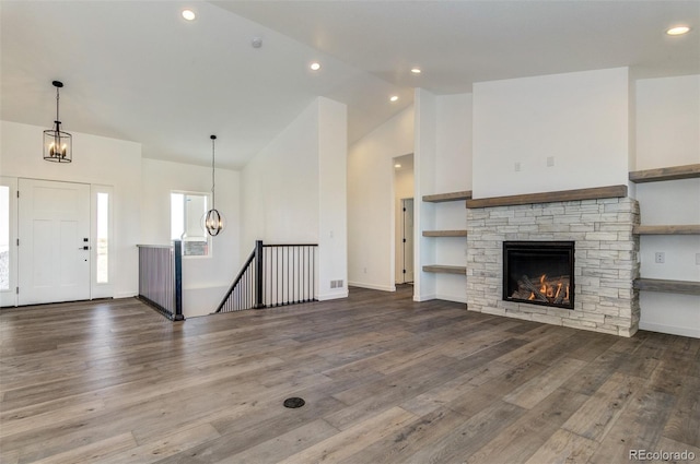 16990 Early Light Dr, Colorado Springs, CO 80908 - unfurnished living room with high vaulted ceiling, a chandelier, a stone fireplace, recessed lighting, and wood finished floors