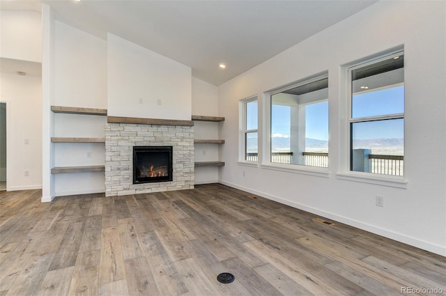 16990 Early Light Dr, Colorado Springs, CO 80908 - unfurnished living room featuring visible vents, baseboards, a stone fireplace, hardwood / wood-style flooring, and vaulted ceiling