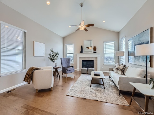 living room featuring a tile fireplace, high vaulted ceiling, wood-type flooring, and ceiling fan