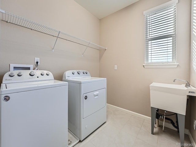 laundry area with washing machine and clothes dryer and light tile patterned floors