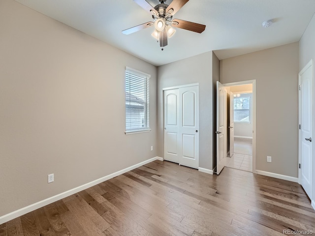 unfurnished bedroom featuring multiple windows, hardwood / wood-style floors, and ceiling fan