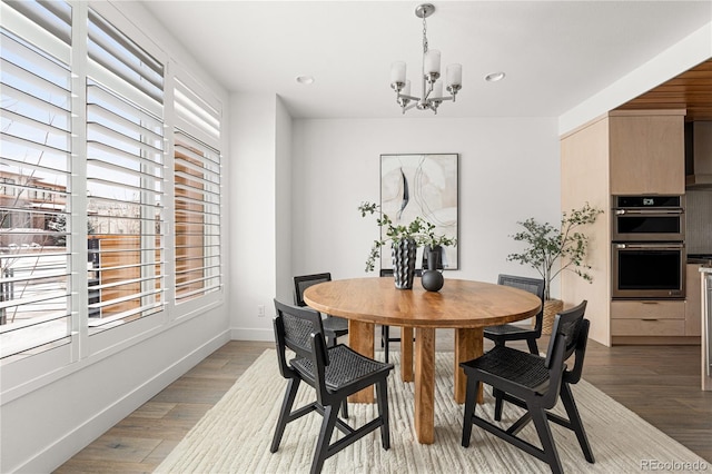 dining space with hardwood / wood-style floors and an inviting chandelier