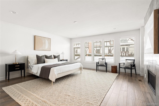 bedroom with hardwood / wood-style flooring and a tile fireplace