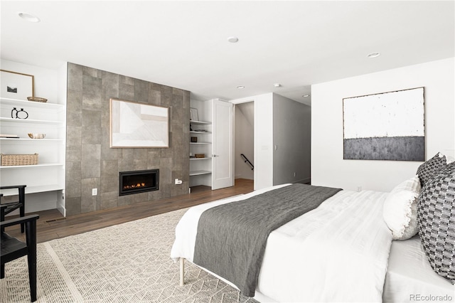 bedroom featuring a tile fireplace and wood-type flooring