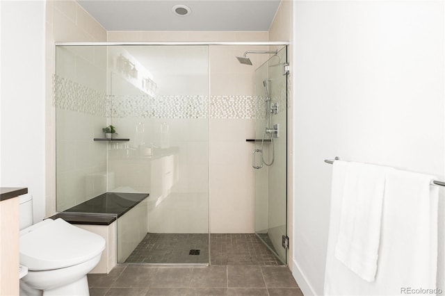 bathroom featuring toilet, a shower with door, and tile patterned flooring