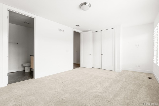 unfurnished bedroom with a closet, connected bathroom, and carpet