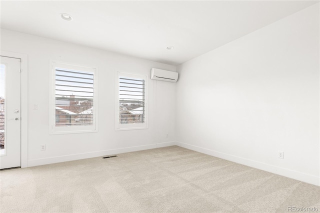 empty room featuring a wall mounted AC and light colored carpet