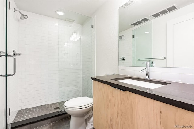 bathroom featuring toilet, tile patterned flooring, walk in shower, and vanity