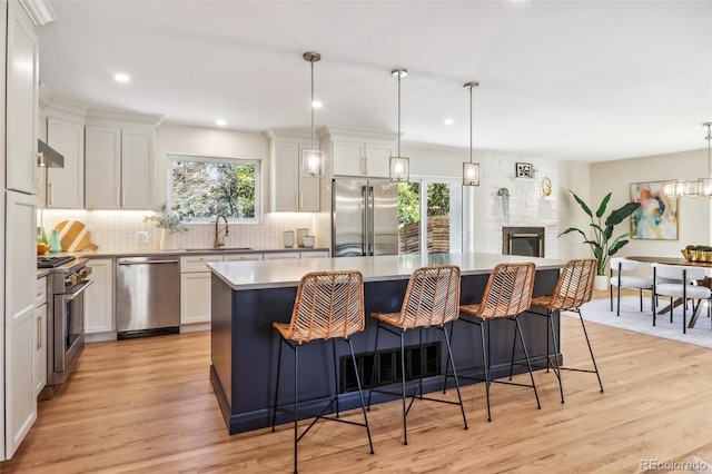 kitchen featuring pendant lighting, a center island, white cabinetry, and high end appliances