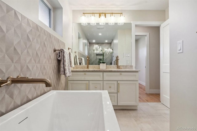 bathroom featuring tile patterned flooring, vanity, tile walls, and a washtub