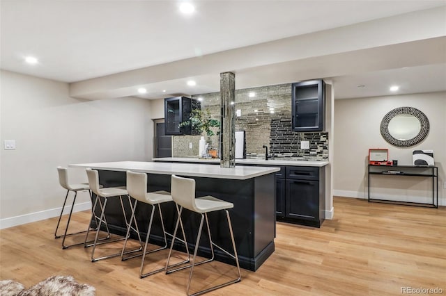 bar with tasteful backsplash, light hardwood / wood-style flooring, and sink