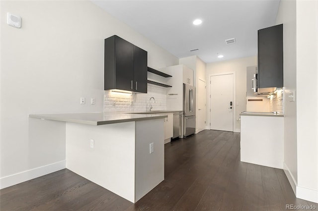 kitchen with dark hardwood / wood-style floors, kitchen peninsula, sink, and appliances with stainless steel finishes