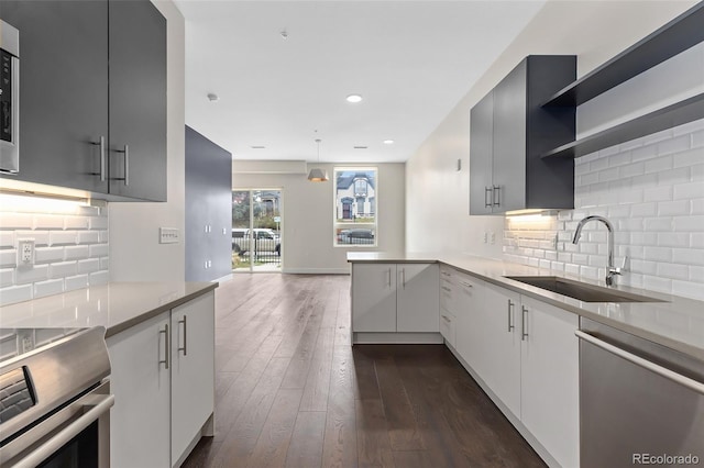 kitchen featuring dark wood-type flooring, sink, stainless steel dishwasher, tasteful backsplash, and kitchen peninsula