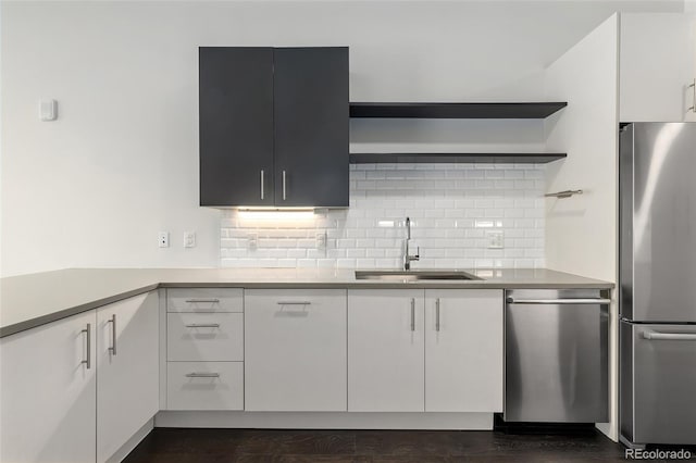 kitchen with decorative backsplash, white cabinetry, sink, and appliances with stainless steel finishes